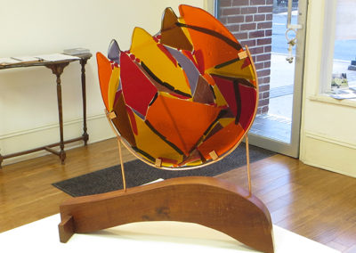 “Fireball”   fused glass, copper and wood by Ellen Rebarber