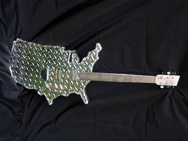 American Prototype – laminated wood cut to USA shape, faux diamond plate, electric guitar parts, hand polished metal fret board with hand set frets, paint – owned by collector
