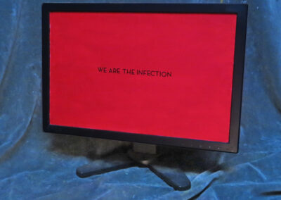 “We Are The Infection” – repurposed computer monitor, day glow paint stick on letters – 18″ x 16″ x 6″